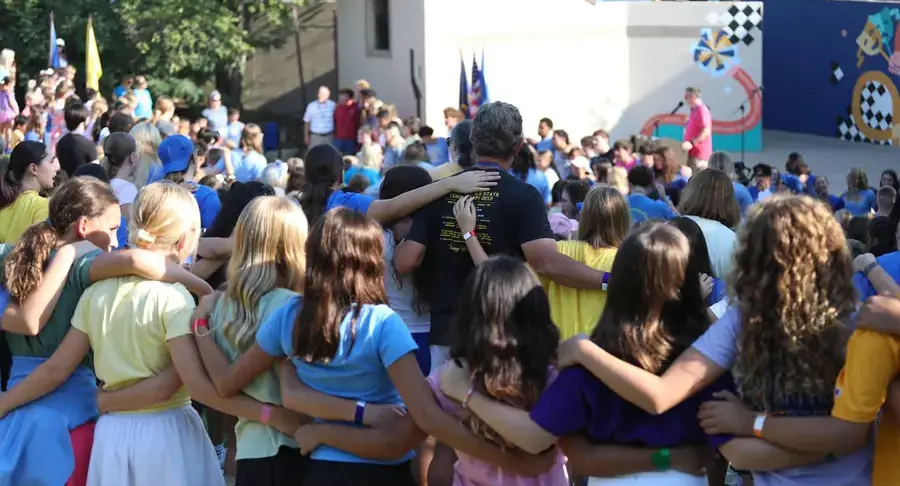 Arms around each other while singing the school song at the whole-school opening assembly