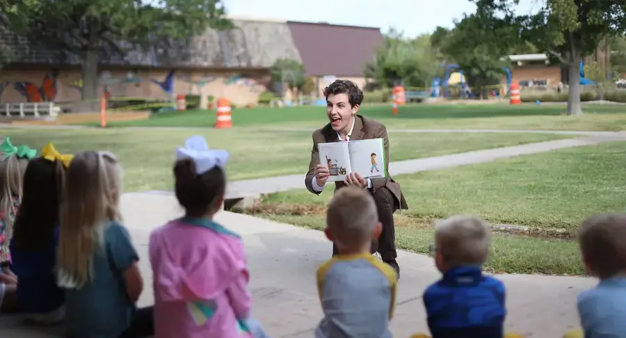 Upper school faculty reading to early childhood students in the quad