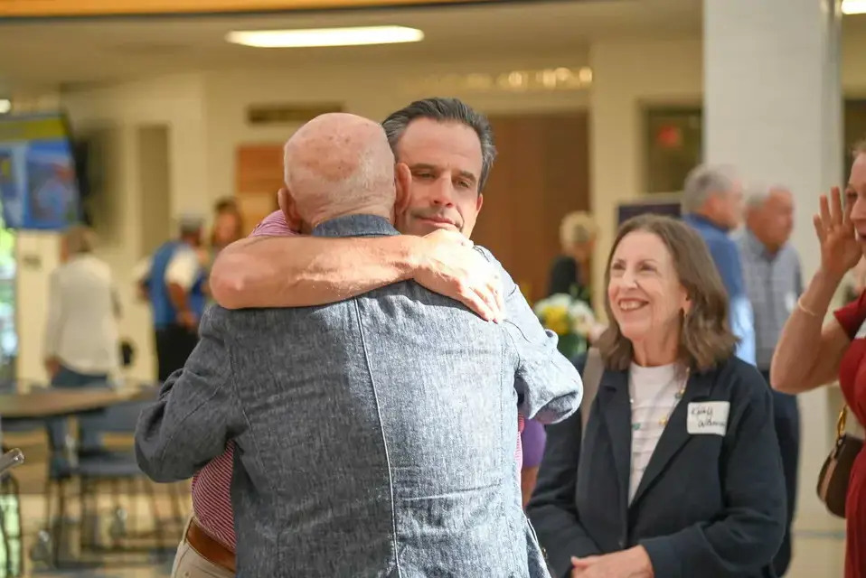 Alumni parent hugs a favorite teacher at a fine arts community event