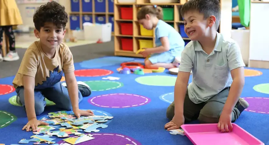 Early childhood students doing puzzles on the floor