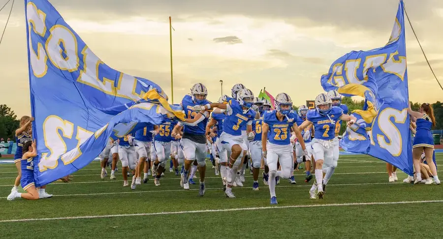 The varsity football team charges onto the field