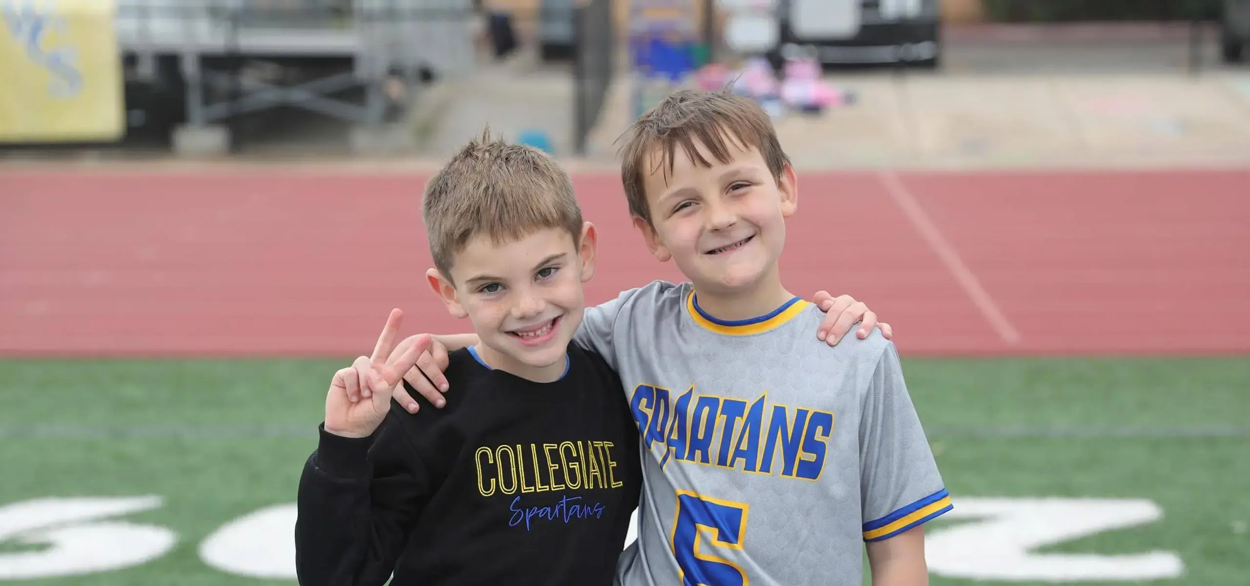Students on sports field posing with peace signs and smiling