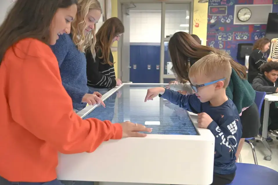 Early Childhood and Upper School students working together on the Anatomage Table in the biology classroom.